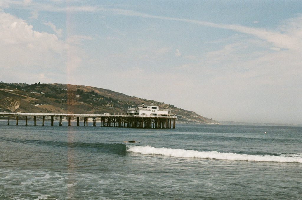 Experience the beauty of Malibu Pier with waves gently crashing under a bright blue sky.