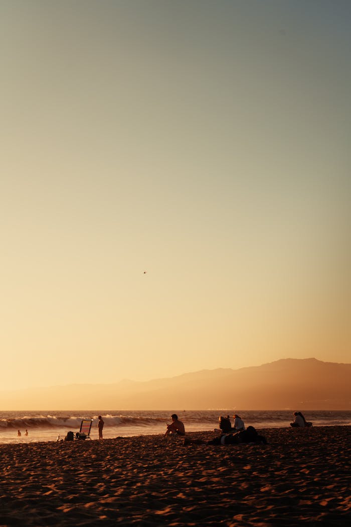 A serene sunset over a Los Angeles beach, showcasing hills and the Pacific Ocean.