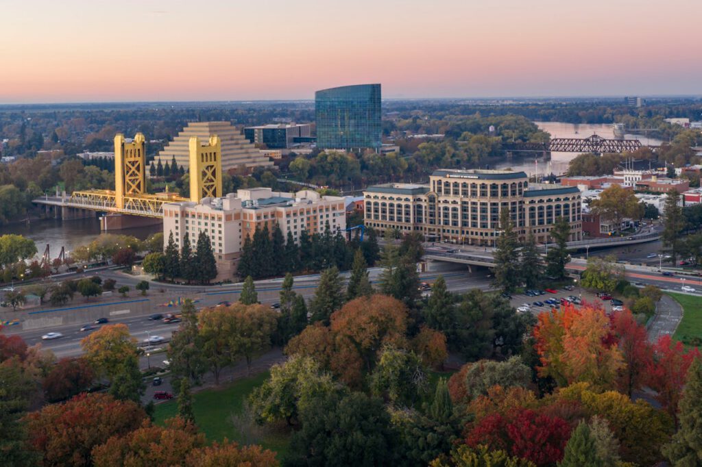 A stunning aerial view of Sacramento featuring the iconic Tower Bridge and autumn foliage at sunset.
